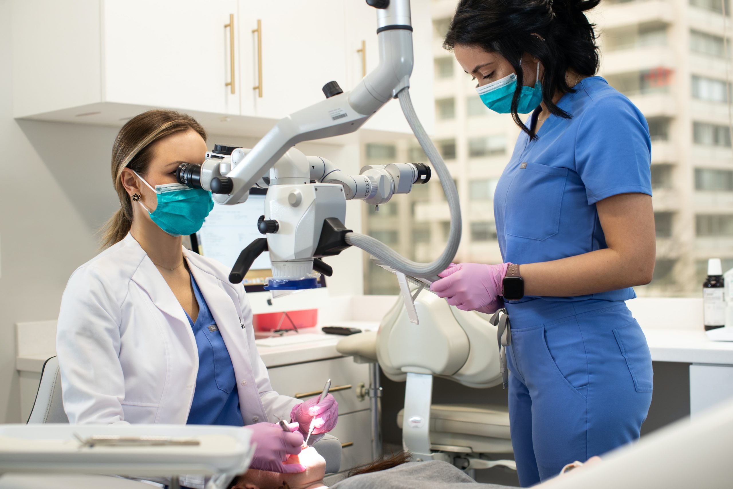 Diverse dental team of Female dentist and dental assistant operating on a female patient.